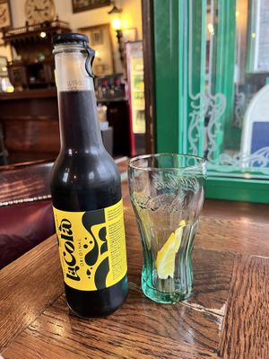 La Cola and interior in background, old pub vibe  at Public Bar & Vegan Kitchen in Bled