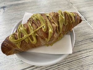 Vegan plain croissant stuffed and drizzled with pistachio cream. You can also buy jars of the pistacchio cream.   at Feliz Cafe in Peschiera Del Garda