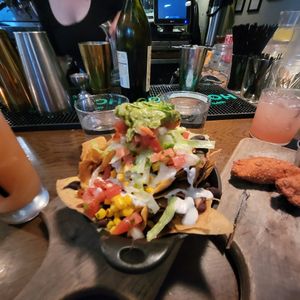 NACHOS housemade ‘cheese’ sauce, black beans, cumin crema, pickled jalapeno, guacamole and  PHILLY STEAK EMPANADAS ‘Cheese’, corn, pico de gallo, spicy ketchup at Bar Bombon in Philadelphia