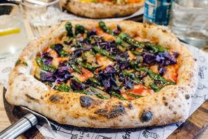 Sourdough Pizza with vegan mozzarella, caramelised onions, roasted courgettes, homemade pesto and red basil leaves. at Purezza in Brighton