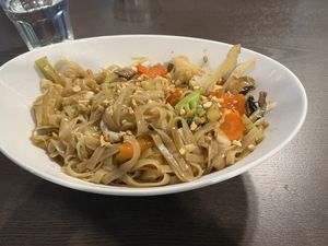 Pad thai. Flat rice noodles with tofu and veg. Topped with peanut pieces. Served in a curved oval bowl    at Veggo Sizzle in Adelaide