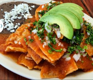 chilaquiles en salsa roja 
acompañados de frijoles refritos

chilaquiles  (fried tortilla chips)
in red sauce
served with fried beans
topped with onion ,cilantro and avocado at Las Delicias Fonda Vegana y Vegetariana  in Cancun