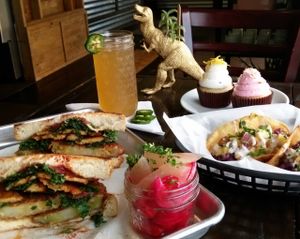 Dixie Dharma's fried green tomato sandwich with tempeh bacon and house pickled veg, jalapeno keylime kombucha from Humble Bumble, and lemon-lavender & raspberry-coconut cupcakes from Valhalla Bakery. All vegan. Photo by @veganorlando at Valhalla Bakery in Orlando