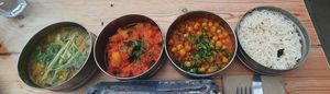 (Vegan tiffin box for one) left to right: Ginger and rhubarb dahl, picnic potato curry, tea steeped chickpeas and rice. at Mowgli in Manchester