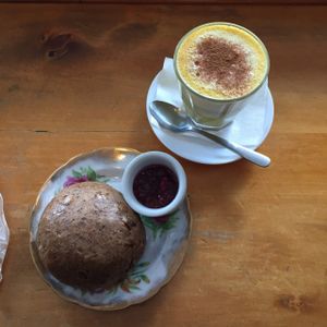 vegan whole meal scone with jam + turmeric latte  at Potpourri Vegetarian Cafe in Dunedin