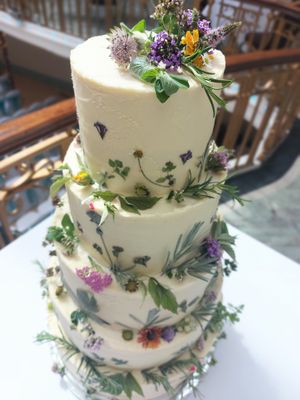 Five-tier vegan wedding cake with fresh flowers and herbs at The Kind Cake Co in Hebden Bridge