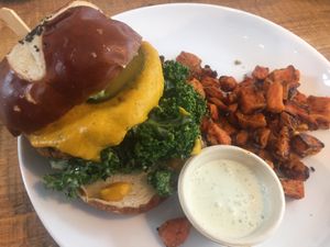 Cited “Best Veggie Burger in America” superfood patty, plantbased cheddar, homemade guacamole, marinated kale, cilantro aioli with sweet potato fries at Love Life Cafe in Miami