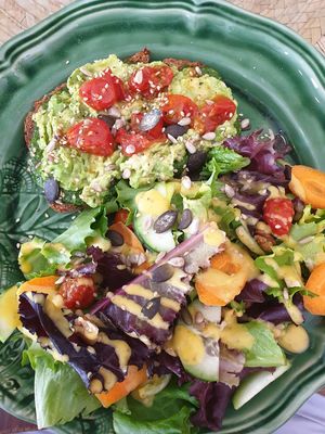 Avocado pesto cherry tomatoes toast with side salad tasty at Dona Flor Cafe in Cascais