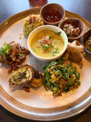 Balinese Rijsttafel - vibrant platter featuring turmeric rice, kemangi curry, tempeh, daily lawar, spiced shredded oyster mushrooms, Sambal Matah calamari, and roasted jack belly. at Moksa in Ubud