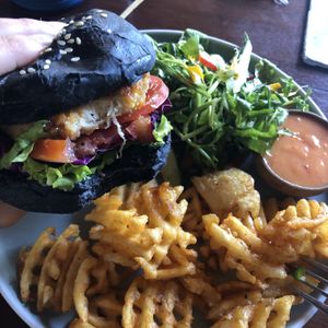 Charcoal Tricken Schnitzel burger with waffle fries  at Pels Supershop in Tibubeneng