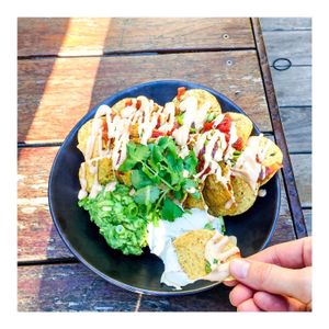 VEGAN NACHOS Organic corn chips on a smashed blackbean base with tomato salsa, spicy chipotle cashew cheese and served with cashew sour cream, smashed avo and coriander. at Island Whole Foods in Cowes