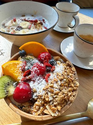In alto porridge con latte vegetale, granola, banana e burro di frutta secca. In basso yogurt di soia naturale con granola, frutta fresca di stagione, semi e frutta secca.  at Paper Plane in Nice