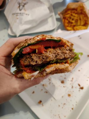 Beyond burger with lettuce, pepper, tomato, spinach, and gherkins on a whole grain bun at Krowarzywa in Krakow