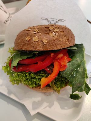 Beyond burger with lettuce, pepper, tomato, spinach, and gherkins on a whole grain bun at Krowarzywa in Krakow
