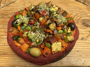 Pizza del Dragon - buckwheat and beetroot dough with vegies and olives on top with sunflower and cashew cheese. So delicious! But take note, this small one was quite substantial!  at Curcuma in El Chalten