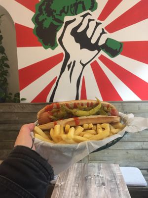 Spicy hot dog in front of the highly instagrammable wall art  at Orinoco Vegan York in York