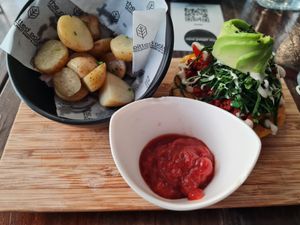 Half of a bagel sandwich with potatoes at The Pitted Date in Playa Del Carmen