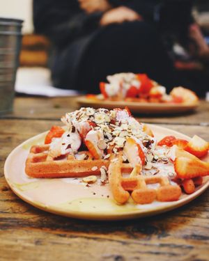 Pink beet waffles topped with hazelnuts, strawberries and oat cream. at Cupcakes and Shhht in East London