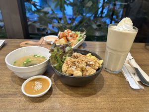 Background: Fried cauliflower wings with accompanied sauce (appetizer). Foreground: Teriyaki bowl with miso soup and peanut sauce & a banana smoothie with coconut whip cream 😋 # at Veganerie Concept - Benjasiri Park in Bangkok