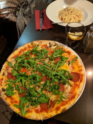 Pizza is spicy salami with mushroom, pepper and rocket. Vegan cheese too. Pasta is carbonara with ham bits at Feca in Stockholm
