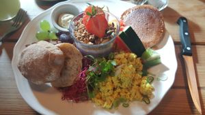 Breakfast menu. American pancakes, scrambled tofu, bread, cheese, yoghurt with granola, fruit, vegetables. at Kaffestuen Vesterbro in Copenhagen