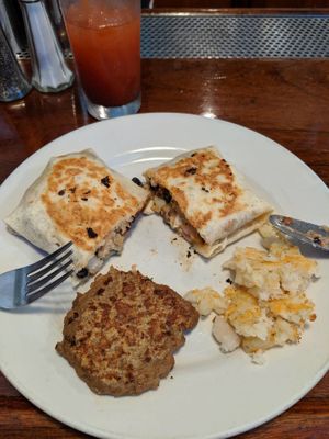 Cheesy Breakfast Burrito: SW Tofu Scramble in a flour tortilla with house-made vegan avocado lime sauce, vegan shredded cheese, & beer-battered hash browns, with Soysage. Yummy! at Spotted Dog Restaurant and Bar in Carrboro
