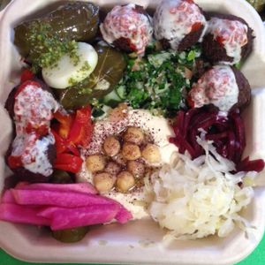 Falafelle Combo is served with Dolma (Rice stuffed Vine leaves marinated in olive oil and fresh lemon juice, paired with mint sauce,) Hummus, Tabbouleh (salad that contains fresh chopped parsley and mint, diced tomatoes, cucumbers and onion mixed with bulgur, olive oil and lemon juice)  and falafel with your choice of toppings and sauces. This plate is 100% Vegan.  at Falafelle in Belmont