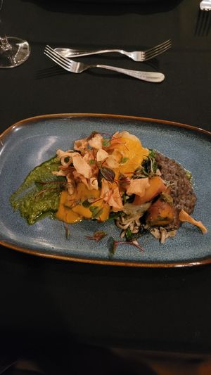 Maitake, garlic greens and cashew cheese stuffed crepe on an applewood smoked lentil daal with a grilled scallion pumpkin seed pesto topped with fried parsnip chips. at Harvest Beat in Seattle