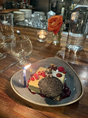 Fresh foraged elderberries and huckleberries on a cheesecake with a black sesame cracker   at Harvest Beat in Seattle
