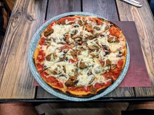 Pizza with vegan cheese and sausage at Rifugio Romano in Rome