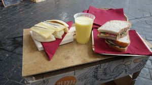 Left: sweet bread with old cheese and honey; middle: mixed juice with banana, orange, and pineapple; right: vegan sandwich with hummus, basil, red onion and olive oil. at Sabores - Food Stall in Sao Miguel