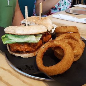 Buffalo crispy chick'n sandwich with a side of onion rings. at Bar Vegandale in Toronto