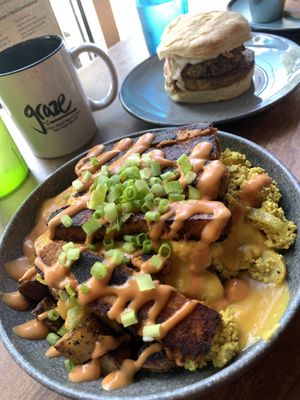 Breakfast bowl made gluten free by subbing potatoes for biscuit on the bottom and subbing double tempeh bacon for the veg sausage. Breakfast sausage biscuit in the back.   at Graze in Nashville