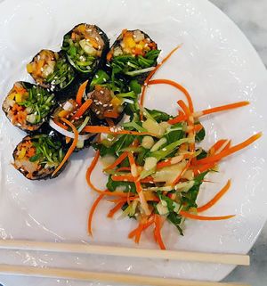 Rainbow roll (mushroom pate, spinach, sunflower sprouts, mango, papaya, carrots, jicama wrapped in nori sheet with  a thai dipping sauce. The side salad comes with a miso ginger sauce at SpaJuiceBar in Fort Lauderdale