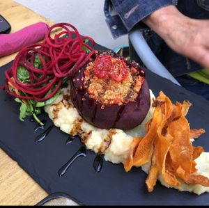 baked beetroot stuffed with quinoa and glazed carrots. sever on celeriac mash and sweet potato crisps and side salad  at Amala Conscious Food in Bournemouth