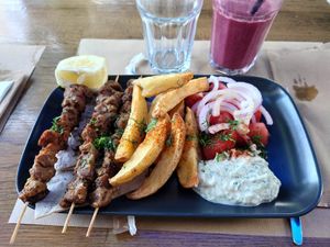 Souvlaki on plate with red smoothie. at Veganaki in Athens