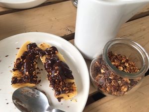 On the left : banana with chocolate sauce and nuts. On the right : homemade granola and plant milk at Joe's Place in Pico