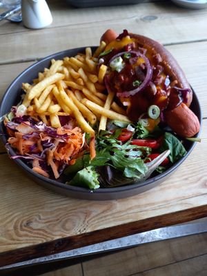 Melted Vegan Chedder with Vegan "Bacon" pieces on a Vegan hotdog in a Bun with Chips & Salad! at Super Natural Newcastle in Newcastle Upon Tyne