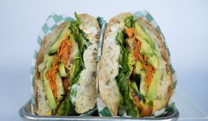 Just Veggies Sandwich made from avocado, seasonal greens, tomato, red bell pepper, cucumber, mushroom, onions, brown mustard, vegan mayo on a toasted ciabatta at Glowing Plant Based Eatery in Los Angeles