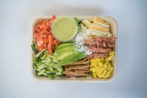 Vegan Cobb Salad made from tofu scramble, avocado, seasonal greens, tomato, cucumber, olive, vegan ham, vegan cheese, vegan bacon and vegan ranch dressing at Glowing Plant Based Eatery in Los Angeles
