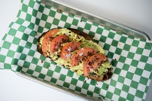 OG Avocado Toast made from avocado, tomato, onion, olive oil, salt and pepper, chili flakes on a lightly toasted olive bread at Glowing Plant Based Eatery in Los Angeles