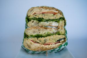 Chickpea Tuna made from homemade chickpea tuna salad, vegan cheese,  seasonal greens, tomatoes, pickles, onions, vegan mayo, and cucumber on toasted ciabatta bread at Glowing Plant Based Eatery in Los Angeles