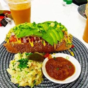 Mighty wyze Hotdog: vegan bratwurst with cashew cheese, diced tomato, plenty of avocado, red onion and signature cheeky sauce. Served on a spelt bun with a side of creamy potato salad and tomato relish. at Cheeky Yam in Cairns