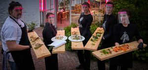 Safe dining: the cooking staff serving on long wooden boards. at Mediamatic ETEN in Amsterdam