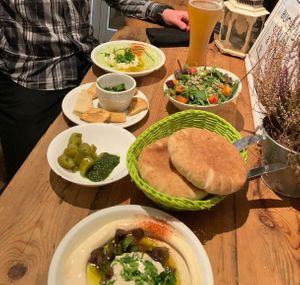 Counter-clockwise: Avocado hummus, garlic and date dip, schug (with pickles), mushroom hummus, pita, and friends salad at Hummus & Friends in Berlin