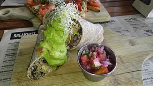 BLACK BEAN & BROWN RICE BURRITOS
onions, green chiles and raw cashew vegan cheese sauce. Served with pico de gallo and homemade guacamole  at Holi Vegan Kitchen in North Miami Beach