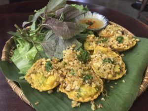 Banh Khot 
Vietnamese mini pancakes topped with mushrooms, scallions and with VEGAN fish sauce. 
Served with an assortment of greens.
This takes 20-25 minutes to prepare. at Pi Vegetarian Bistro in Ho Chi Minh City