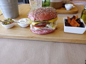 Bean burger on a very narrow piece of wood, with tiny portion of vegetable crisps 😂 at Earth Shop and Cafe in Carvoeiro