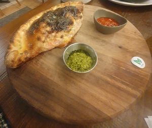 Meatless meatballs calzone: A folded pizza filled with meatless 'meatballs', vegan MozzaRisella, red peppers, calabrese sauce, pesto, olives, spinach & garlic. at Zizzi - Trafford Centre in Manchester