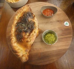 Meatless meatballs calzone: A folded pizza filled with meatless 'meatballs', vegan MozzaRisella, red peppers, calabrese sauce, pesto, olives, spinach & garlic. at Zizzi - Trafford Centre in Manchester
